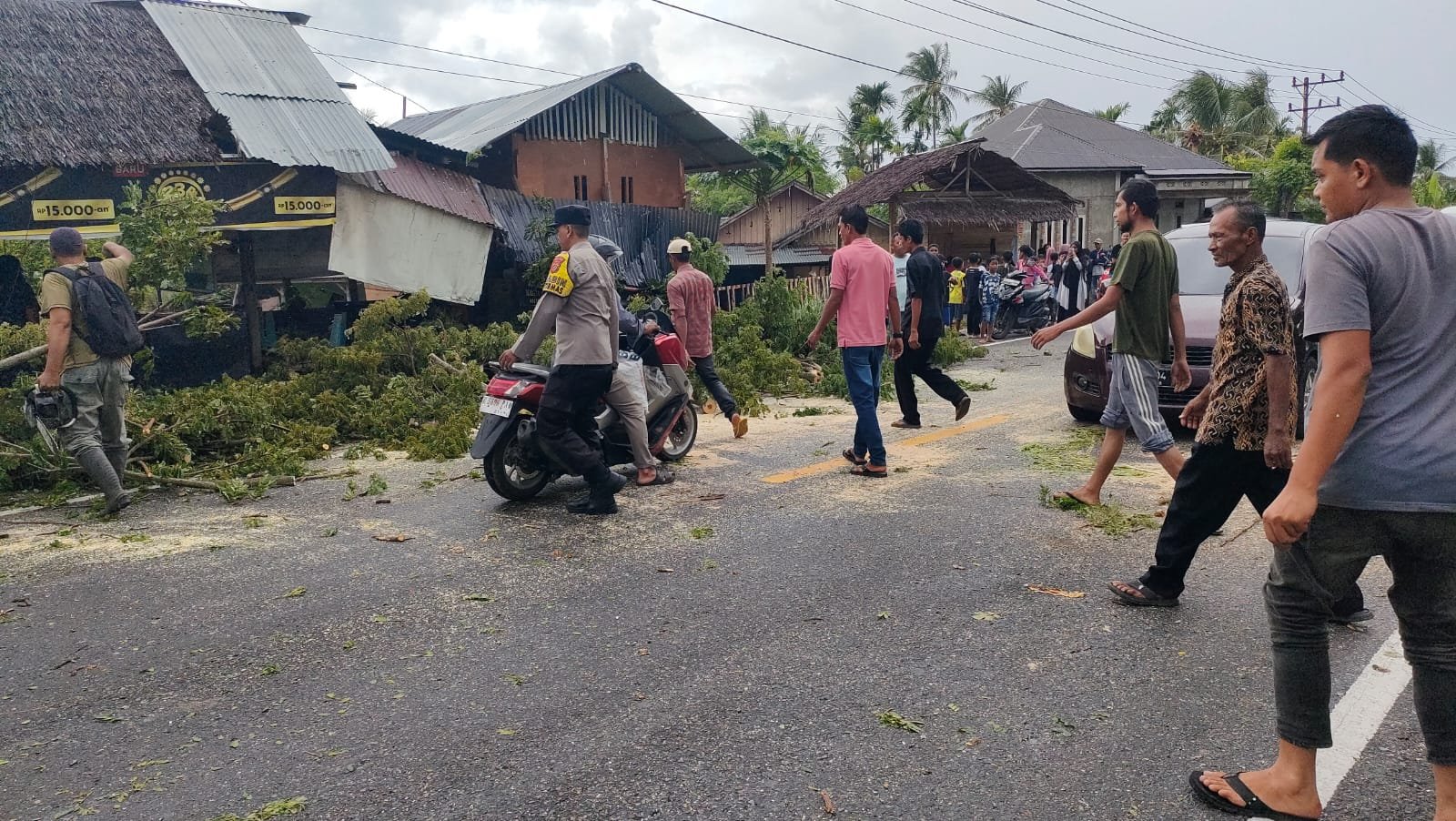 POHON TUMBANG AKIBAT HUJAN DISERTAI ANGIN KENCANG, AIPTU FAISAL AJAK WARGA BERSIHKAN JALUR BANDA ACEH–MEDAN